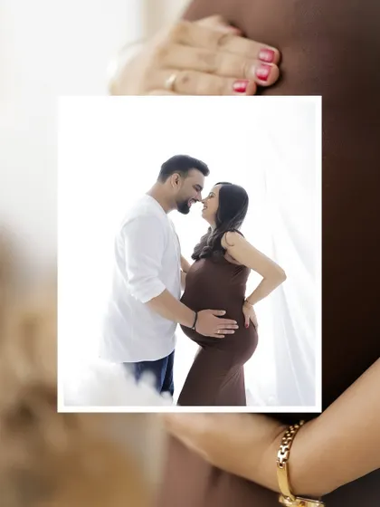A creative "photo-in-a-photo" shot, focusing on an intimate portrait of the couple held against the backdrop of the baby bump.