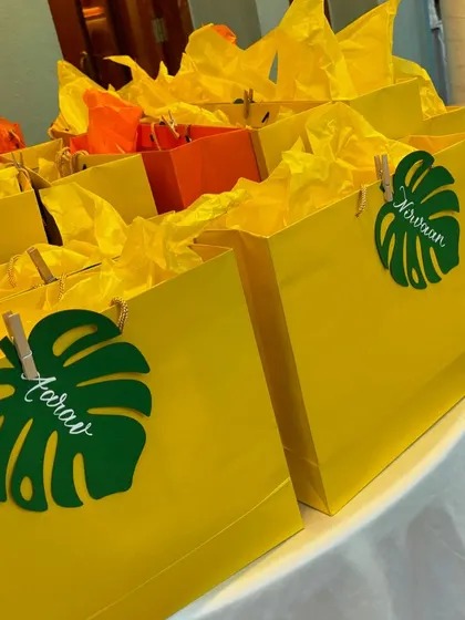 Here are the finished monstera leaf name tags attached to bright yellow gift bags. It's so rewarding to see how a small, personalized touch can bring a party theme to life.