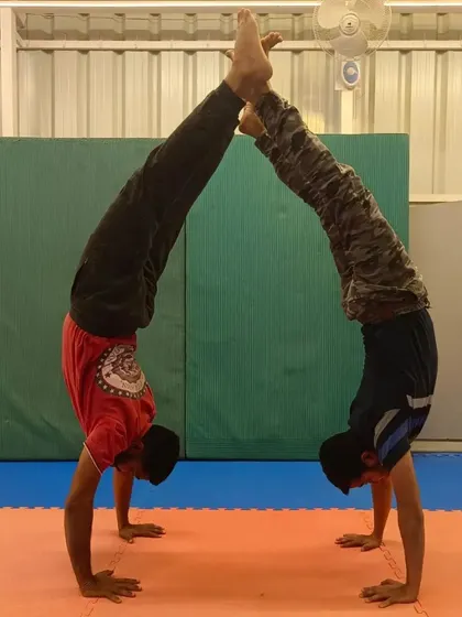 Two of my older students practicing a partner handstand. This advanced calisthenics move shows the level of skill and coordination they have developed.