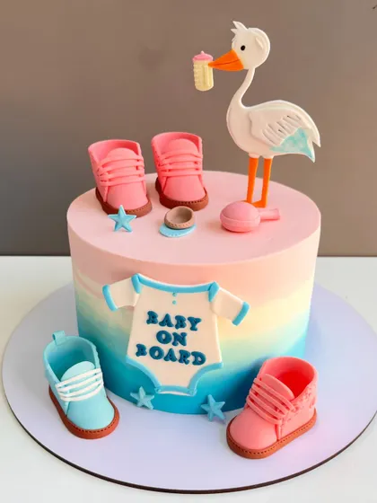 Welcoming a new arrival is a joyous occasion, and this baby shower cake captures that sweetness. It features a smooth, blended pastel frosting and is decorated with handcrafted fondant details like tiny baby shoes, a stork, and a "Baby on Board" onesie.