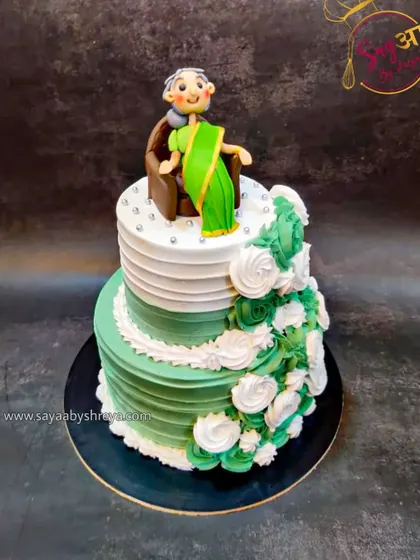 A two-tier cake in elegant green and white, topped with a sweet figurine of a grandmother sitting contentedly. This was designed to honor the matriarch of a family with grace and style.