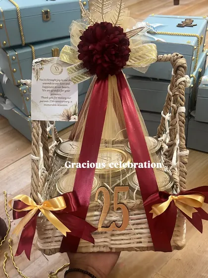 Celebrating a 25th anniversary is a grand affair, and the return gifts should be just as special. This luxurious basket hamper, decorated in rich maroon and gold, is filled with five different jars of delicious eatables and marked with a '25' to honor the silver jubilee.