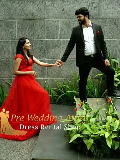 A couple in a garden setting. The woman wears a red ruffled gown with a short trail, a style that is both elegant and easy to move in.