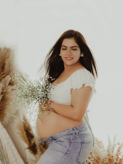 A natural and joyful portrait from a lifestyle session. The focus is on the mother-to-be's radiant smile and the beauty of her bare bump.