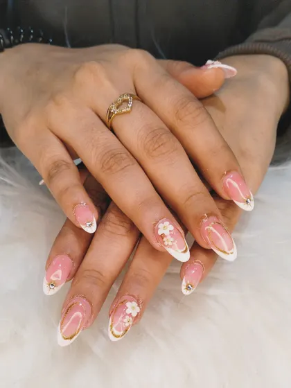 A gorgeous and intricate design perfect for a special occasion, featuring French tips outlined in gold and accented with 3D white flowers.