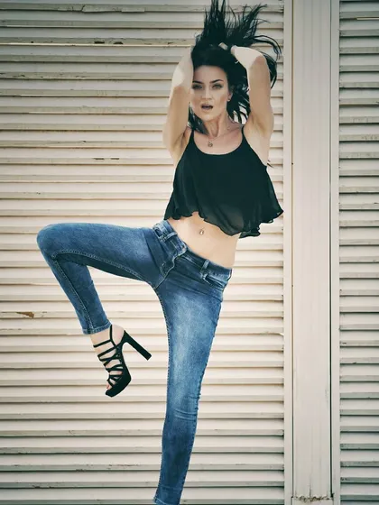 An energetic, high-fashion pose for a denim brand. The combination of high heels and casual jeans, along with the dynamic action, creates a memorable and powerful shot.