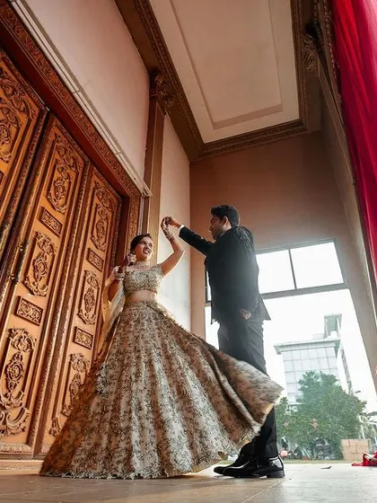 A grand reception portrait. The couple twirls in front of massive, ornate doors, creating a sense of fairytale romance.
