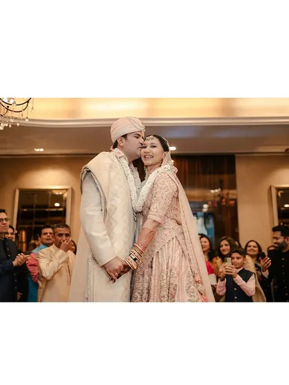The groom's kiss, surrounded by the happy faces of family and friends. This photo captures the public celebration of a private love.