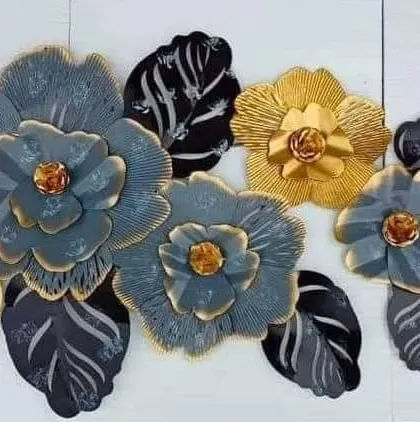 A close-up of a floral metal wall art piece. The combination of grey, black, and gold gives it a modern and artistic feel.
