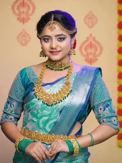 A full-view of the bride, showing the beautiful embroidery on her blouse and the complete set of bridal jewelry.