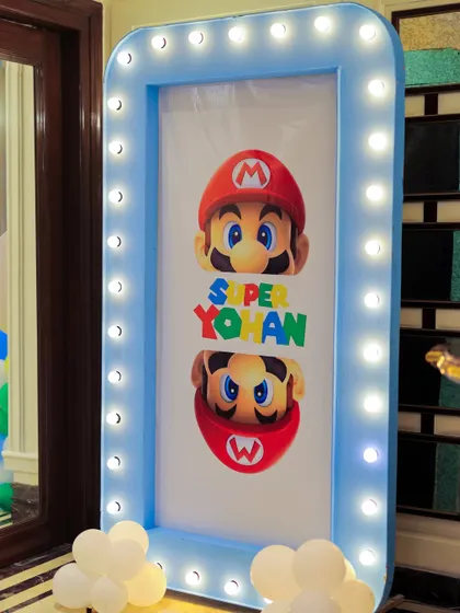 A personalized "Super Yohan" welcome sign with a Mario theme, framed in a blue marquee-lit border. This custom sign makes the birthday boy the hero of his own game.