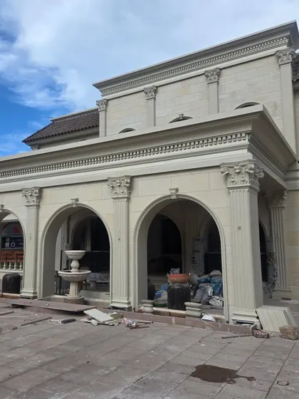 The exterior of the Veerabhavana Villa under construction, showing the grand arches and classical columns that define its Mediterranean architectural style. The use of stone cladding gives the home a sense of permanence and grandeur.