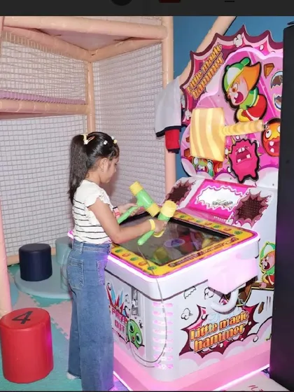 A girl plays the "Little Magic Hammer" game in our well-equipped arcade area.