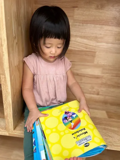 A child proudly carries a stack of books she has chosen from our library, ready for a quiet reading session.