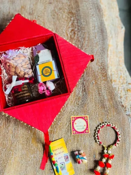 The contents of the red house-shaped box, including a Lumba rakhi for a sister-in-law, almonds, and cookies.
