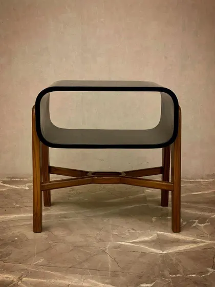 The 'Plain Jane' side table offers immaculate mid-century vibes. It has a sleek black gloss top with a useful storage nook and a solid teak base with crossed legs.