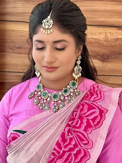 A close-up on the soft pink eye makeup, paired with a beautiful emerald and diamond necklace.