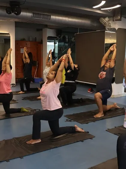 Members in the Low Lunge pose (Anjaneyasana), a great stretch for the hips and thighs, practiced together as a group.