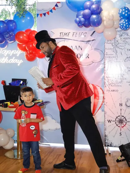 A magician entertains the birthday boy at his "Time Flies" themed party, adding a touch of wonder to the celebration.