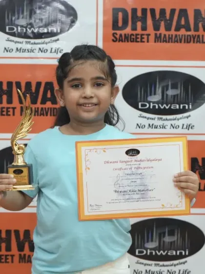 A young girl proudly holds her certificate and trophy.