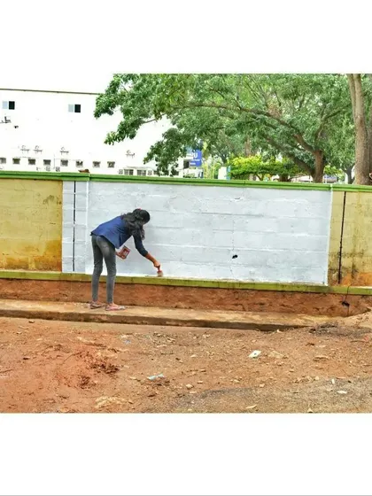 Before the art begins, the canvas must be prepared. Here, an artist is applying a base coat to a large outdoor wall in Mysore.