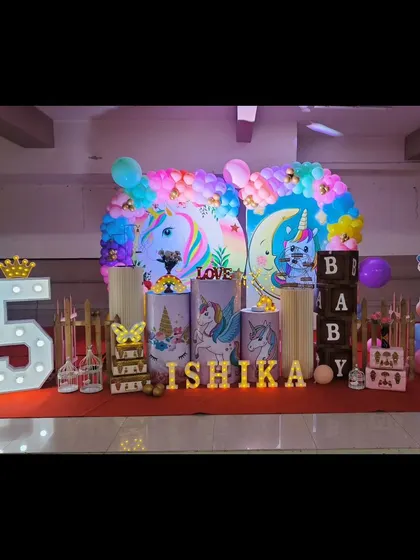 Our unicorn theme is pure magic. This setup for Ishika's birthday features pastel unicorn illustrations on pedestals, a rainbow balloon arch, and light-up letters for an enchanting party.