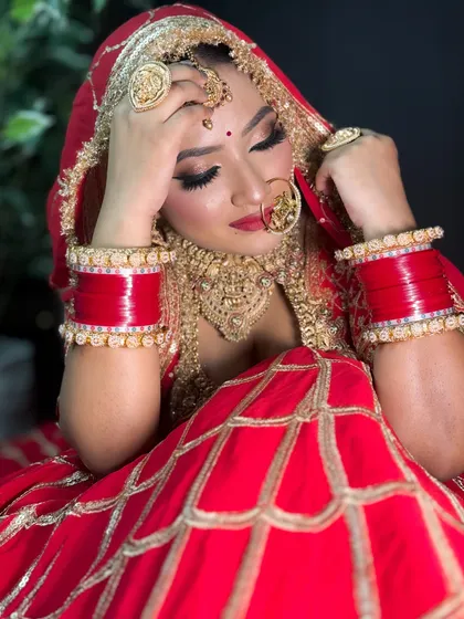 A thoughtful pose from a bride in her red lehenga. The lighting beautifully captures the shimmer in her eye makeup and the richness of her outfit.