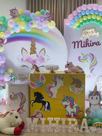 A close-up of the main unicorn backdrop, featuring a neon "Happy Birthday" sign and a rainbow balloon arch.