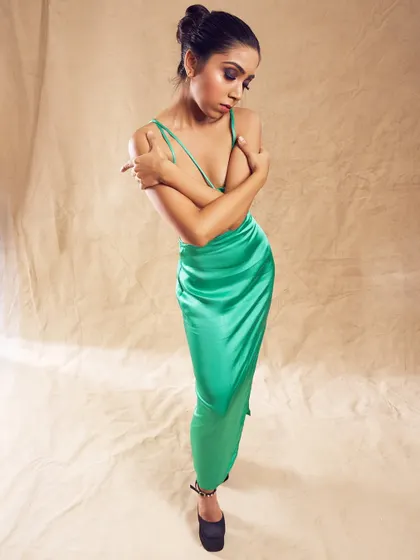 A full length view of a dramatic evening look. The dark, smokey eye makeup provides a beautiful contrast to the vibrant emerald green of the satin dress, creating a cohesive and stunning effect.