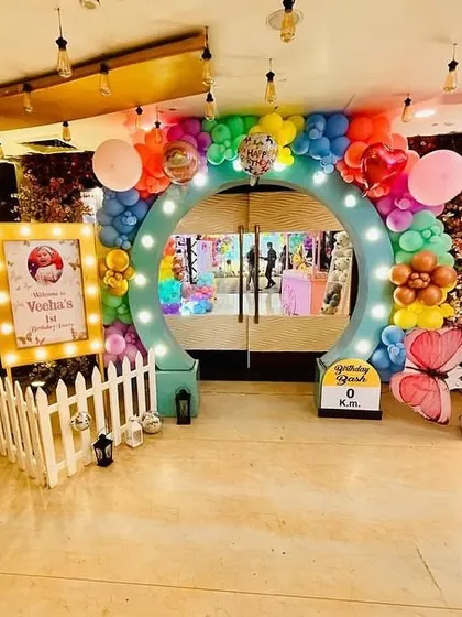 The entrance to the butterfly-themed party, featuring a circular balloon arch, a welcome sign, and a large light-up 'ONE'.