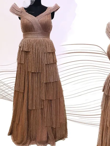 A studio shot of the shimmered rose gold gown, showing the intricate pleating and tiered skirt design.