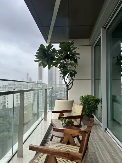 The Lumen House balcony is an urban retreat featuring mid-century modern wooden chairs with woven cane details. Paired with lush greenery, it’s a perfect spot to enjoy the city view in a natural, serene setting.