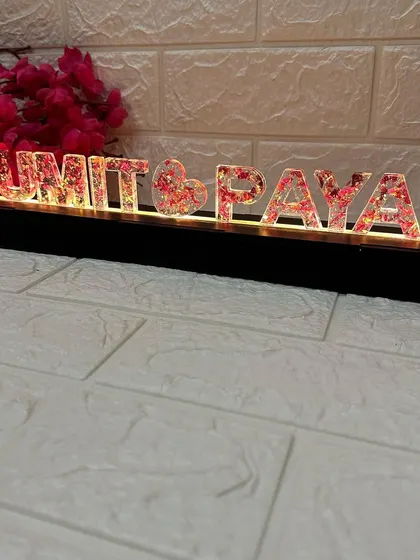 This LED name stand is a unique way to preserve wedding memories. The couple's names are cast in resin with their varmala petals inside and illuminated from below.