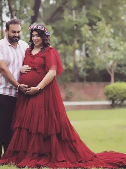 A full-length view of the tiered maroon gown, showing off its long, flowing train. This dress provides a romantic and elegant option for your maternity photoshoot.