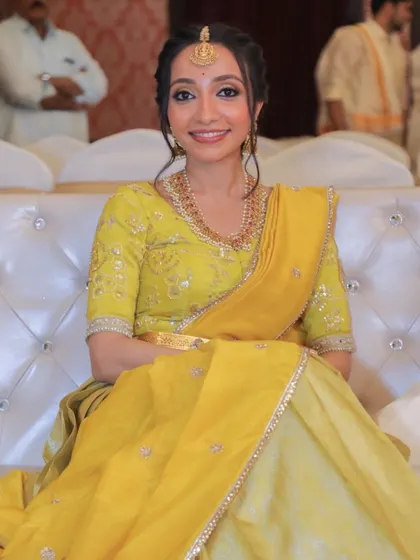 Seated and smiling, she looks effortlessly graceful. The makeup is designed to be light and comfortable, ensuring she can enjoy the event while looking her absolute best.