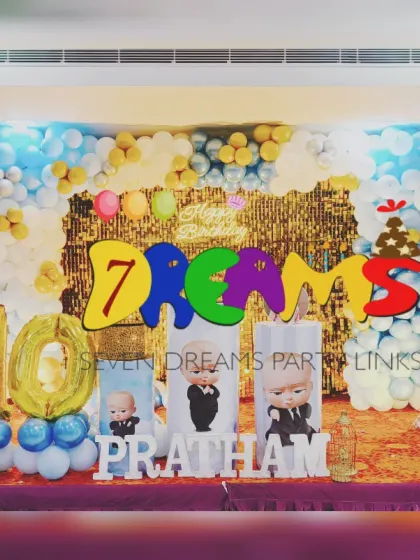 A Boss Baby theme for a 10th birthday celebration. This setup includes large foil balloons for the age, a gold shimmer backdrop, and personalized photo cutouts alongside the character props.