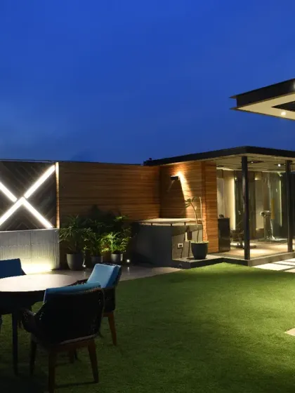 The upper terrace of the Screen House is designed as a private retreat, combining wellness and relaxation. This evening view shows the landscaped green area and the adjacent gym, illuminated for nighttime use.