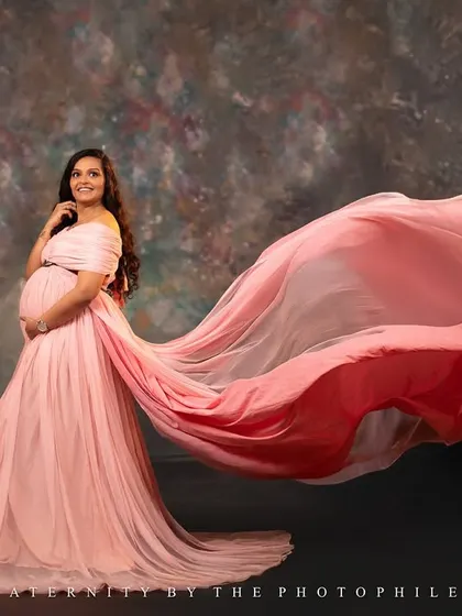 A stunning solo shot showcasing the incredible length and flow of the pink gown against a classic painted backdrop.