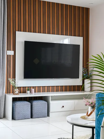 A modern TV unit with a fluted wood panel background. The clean lines of the white console provide ample storage, while the simple decor keeps the look uncluttered and stylish.