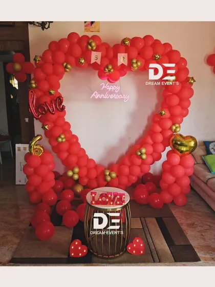 A romantic anniversary decoration for an at-home celebration. I created a large heart-shaped balloon arch in red and gold, with a "Happy Anniversary" neon sign to make the occasion feel extra special.