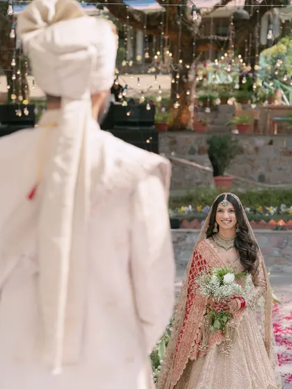 The bride's joyful expression as she sees her groom for the first time, captured in a beautiful 'first look' moment during their lakeside wedding.