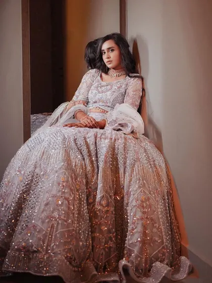 A dramatic shot of the bride seated, her voluminous lehenga filling the frame.