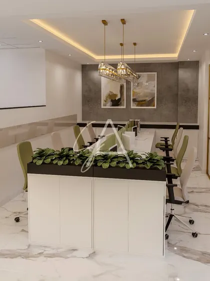 A collaborative workspace featuring a central planter and subtle green accents on the partition screens. The combination of a marble-patterned floor, gold-framed glass walls, and modern lighting creates a sophisticated and fresh office interior.