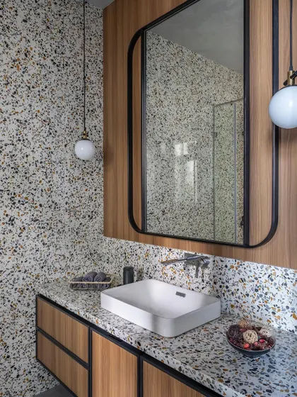 We love the playful yet sophisticated look of terrazzo. In this guest bathroom, we used terrazzo on both the countertop and the wall, pairing it with warm veneer cabinetry for a modern and textural feel.