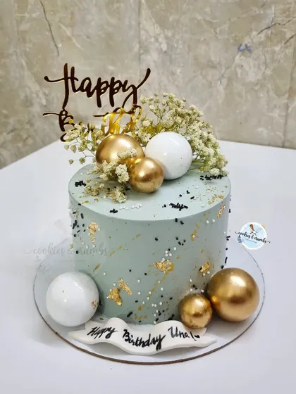 A simple and elegant design featuring a sage green cake with gold leaf, baby's breath, and a mix of gold and white spheres.