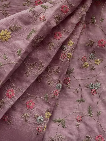 This embroidered slub silk in a dusty rose hue features delicate multi-color floral embroidery, making it a sophisticated choice for an elegant suit or gown.