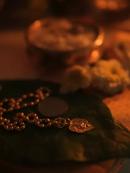 A macro shot of a gold chain and coin on a betel leaf, part of the Vishu kani, symbolizing prosperity for the new year.