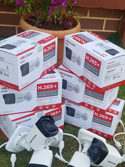 A complete outdoor setup ready to go, with multiple Hikvision H.265+ bullet cameras laid out on the grass before installation.