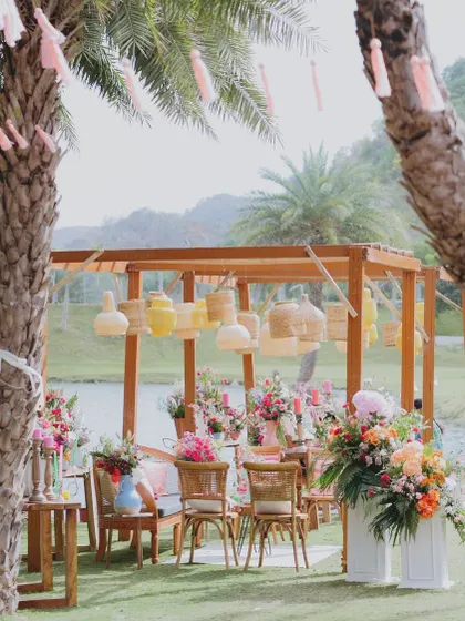 A lakeside lounge setup featuring wooden pergolas, cane lanterns, and vibrant floral pillars. This was a perfect spot for guests to relax and enjoy the celebration.