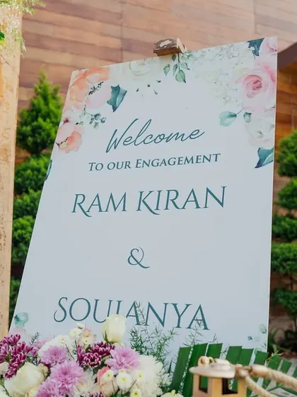 A clean and modern welcome sign for an engagement, surrounded by delicate floral arrangements.